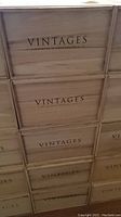 Stacked vintage wooden wine boxes with VINTAGES Wine & Spirits Group branding visible on the side.