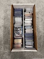 Two-row box filled with vertically organized mixed sports cards protected in plastic sleeves, visible baseball cards including a White Sox player card