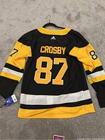 Back view of Sidney Crosby Pittsburgh Penguins NHL jersey on hanger, showing name and number 87 with Adidas logo.