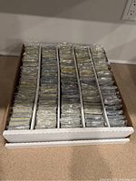 Photo of numerous sealed Pokémon Energy cards individually packaged and organized in rows inside a storage box.