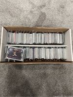 Box filled with numerous NBA trading cards, each protected individually and stacked neatly for collection.