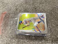 View of a stack of baseball cards in a plastic sleeve showing a player wearing a blue helmet and white uniform with blue pinstripes.