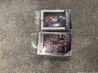 Two NBA basketball cards in plastic sleeves on carpeted floor, showing front designs of players in action: one from the Pro Series and one NBA Hoops card.
