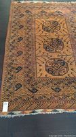 Full view of rug showing three central medallions, borders, and white fringe.