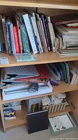 Shelves with various art books and folders, including titles such as 'The Art Pack', 'Drawing from Observation', and 'The Book of Kells'. Folders and portfolios containing papers and art materials are visible.