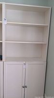 Front view of white bookcase showing three open shelves and two-door cabinet below