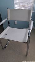 Front view of retro chrome chair with white leather seat and backrest, showing the armrest and frame details.