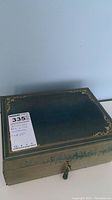 Closed green jewelry box with gold trim and tassel pull