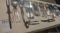 Full view of the laid out complete cutlery set including forks, knives, spoons, serving utensils and nutcracker tools on a tablecloth