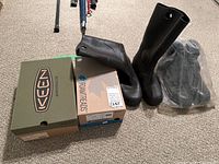 Two pairs of men's boots with their boxes beside them, placed on carpet