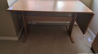 Front view of the wooden office desk showing the main desktop surface, legs, and horizontal base brace.