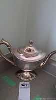 Front view showing overall shape, engraving, handle, spout and pedestal base