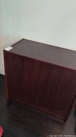 Closed wooden storage cabinet with two doors, dark finish, and flat top.