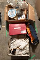 Large cardboard box containing assorted items and a smaller box of dolls