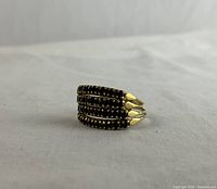 Front angled view of the four-band ring on neutral fabric