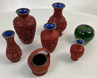 Group shot of all six red carved lacquer pieces (five vases and one basket).