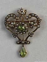 Front view of openwork brooch pendant with central peridot, pearls and drop