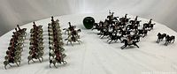 Full spread of painted lead cavalry figures on white and black horses with green apple for scale