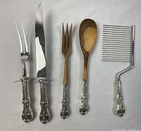 Full view of the five serving utensils showing varying functional parts and ornate sterling silver handles.