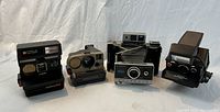Four Polaroid cameras side by side front view