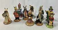 Front view of ten Bunnykins figurines arranged in a row on white background