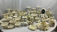Wide view of over 60 Belleek porcelain pieces on table