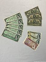 Top view of five uncirculated 1967 Canadian commemorative bills featuring Queen Elizabeth II on front, primarily $1 bills
