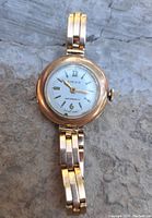 Front view of gold watch on stone background showing dial and bracelet