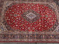 Full view of rug showing red field with central medallion and floral pattern