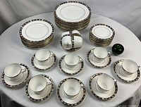Overview of entire set on white tablecloth, showing stacks of plates and arranged cups with saucers