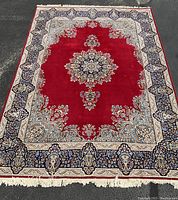 Full view of rug showing red field, central medallion and border