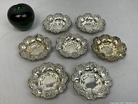Seven dishes arranged with green glass apple for scale