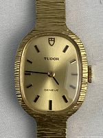 Front view of gold-tone Tudor Geneve watch face on white background
