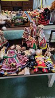 Display of folk dolls and character plush dolls on table, showing bright colorful costumes and various characters.