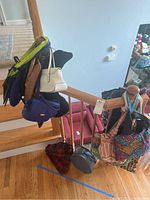 Wide view of purses and totes hung on wooden stair railing, showing different colors and styles.