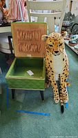Jewelry storage bench with open lid showing plush leopard doll sitting beside it