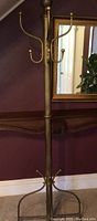 Full view of free-standing brass hat rack against wall