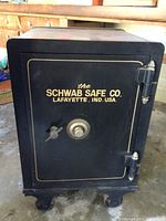 Front exterior of safe showing black painted door with gold logo, combination dial and handle.