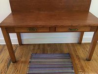 Frontal view showing desk top, two front drawers with brass handles, and square legs