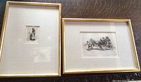 Both framed lithographs side by side on a dark textured surface, showing gold-tone frames and beige mats.