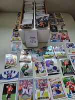 Top-down photo showing the open box filled with large stacks of football rookie cards and a selection of individual cards laid out in front of it.