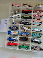 Photo showing top view of 24 Hot Wheels cars in plastic carrying case compartments featuring various color and styles including red, yellow, green, and silver cars