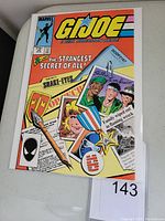 Front cover of G.I. Joe #26 comic book showing the Snake Eyes origin theme with various visual elements including a medal and photographs.