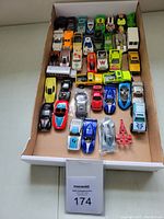 Full view of tray with 40 assorted vintage Hot Wheels cars and trucks arranged in rows, showing varied colors and designs.