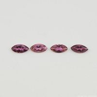 Four marquise-cut pink tourmaline gemstones laid in a row on a neutral background showing color and shape.