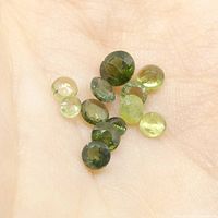 Green round sapphire gemstones held in hand showing size and color variety.