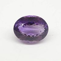 Close up photo of the oval purple amethyst with fantasy cut facets on white background.