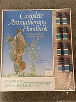 Cover photo shows the Complete Aromatherapy Handbook book and eight essential oil bottles attached to the front. The book cover is blue with an image of a statue and text describing it as a gift set.