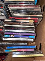 Top view of stacked CDs showing spines with various artist names and album titles including Michael Crawford, King Sunny Ade, Don Carlos, Lucky Dube, and soundtracks.