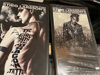 Photo shows two graphic novels of Stieg Larsson's The Girl with the Dragon Tattoo, one sealed and one unsealed.